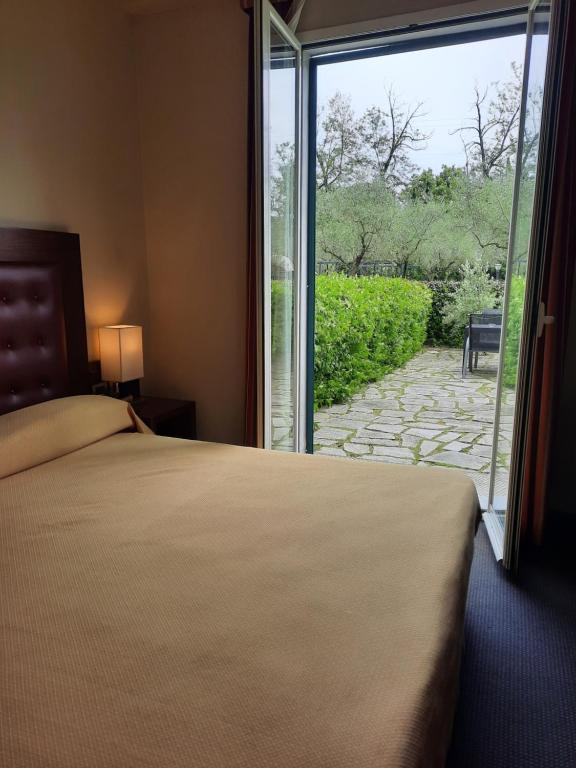 サルザーナにあるSanta Caterina Park Hotelのベッドルーム1室(ベッド1台付)、スライド式ガラスドアが備わります。