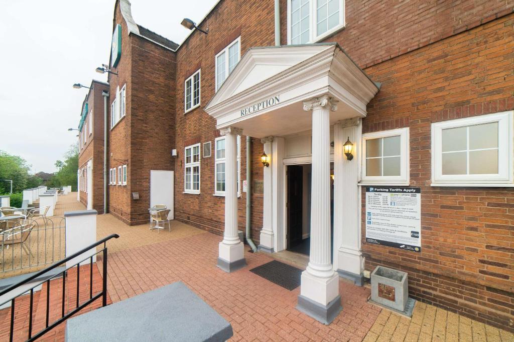 a brick building with a porch with a sign on it at Quality Hotel Coventry in Coventry