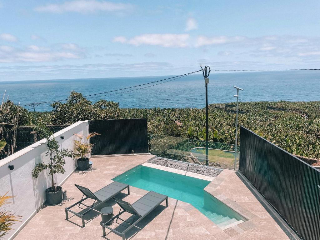 a swimming pool with two chairs and the ocean at La Palma Luxury in Las Ledas