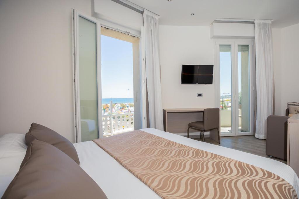 a bedroom with a bed and a desk and a balcony at Hotel Baby in Rimini