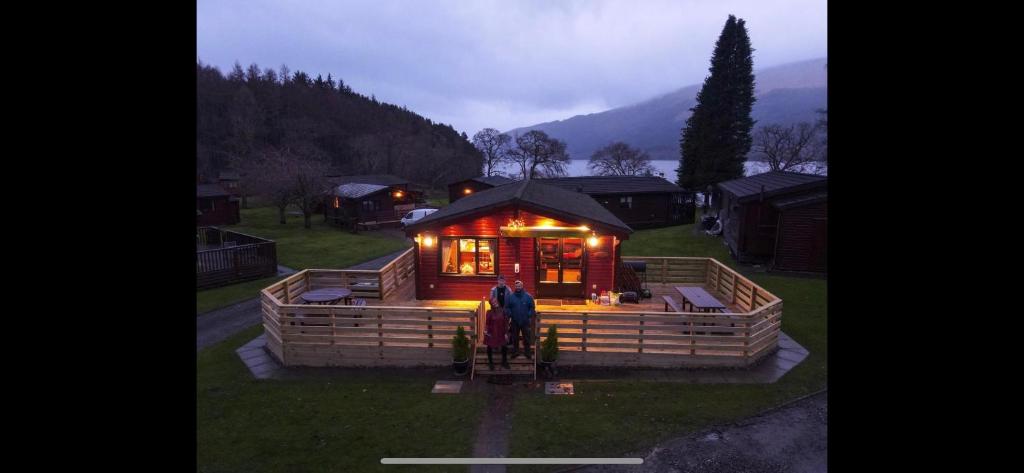 a large wooden cabin with lights in the grass at Ben Lomond Lodge in Rowardennan