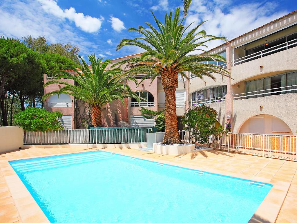 une piscine devant un immeuble avec des palmiers dans l'établissement Apartment Le Florid-7 by Interhome, au Cap d'Agde