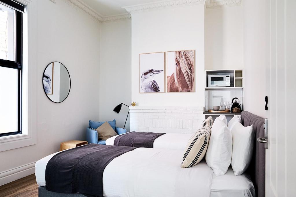 a bedroom with two beds with white walls at Richmond Studios in Melbourne