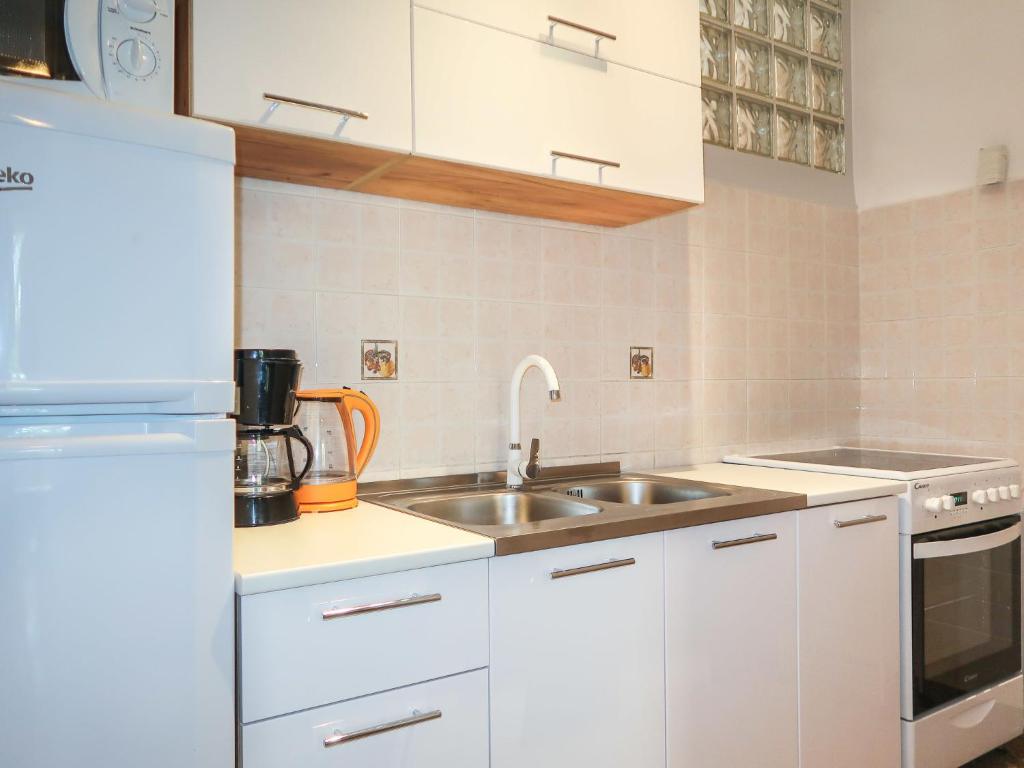 biała kuchnia ze zlewem i lodówką w obiekcie Holiday Home Maravic-1 by Interhome w mieście Dobrinj