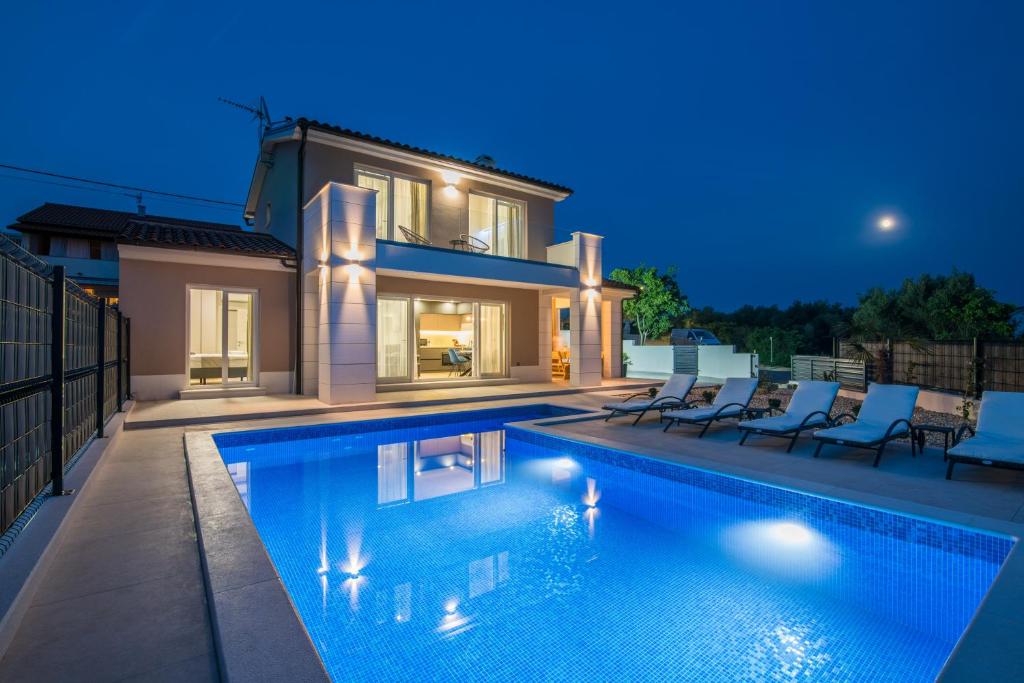 une villa avec une piscine la nuit dans l'établissement Villa Periska, à Krk