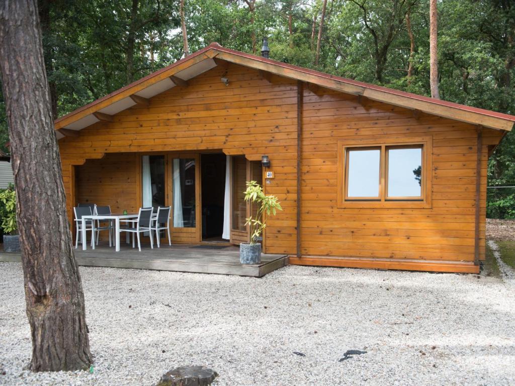 eine Blockhütte mit einem Tisch und Stühlen auf einer Veranda in der Unterkunft Holiday Home De Brenkberg-1 in Schinveld