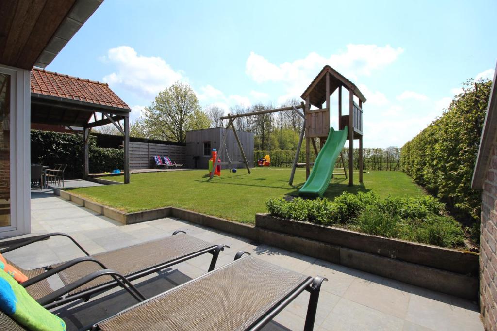 un patio trasero con un parque infantil con un tobogán en Het Rustplekje, en Alveringem