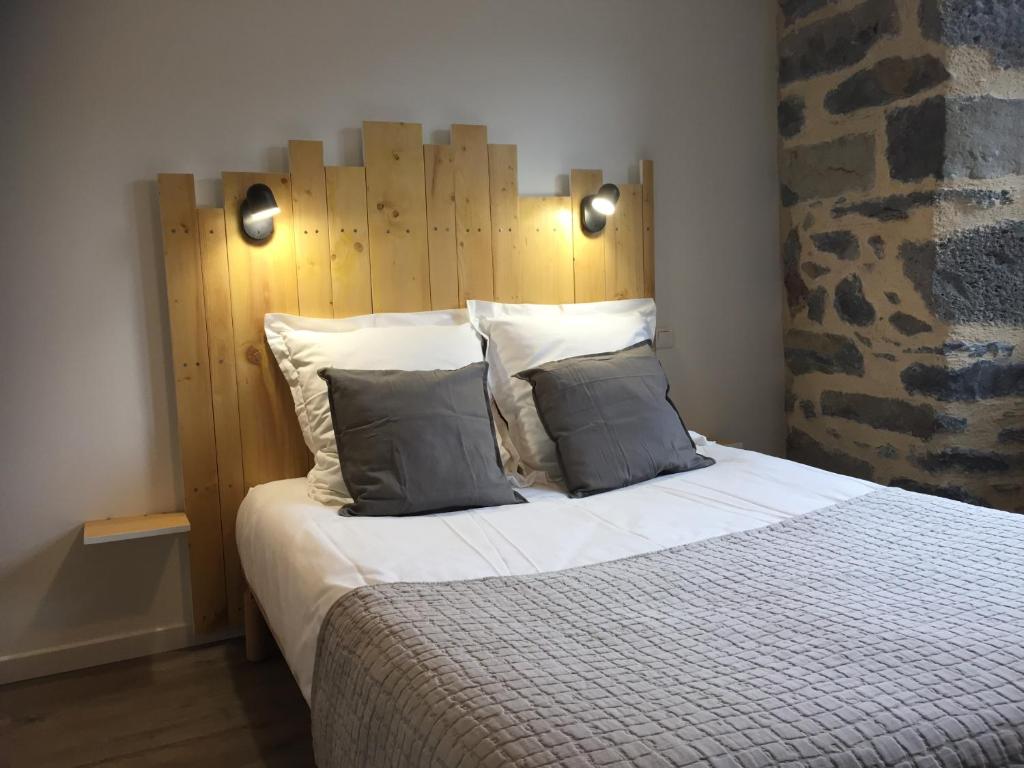 a bedroom with a large bed with a wooden headboard at Hôtel Restaurant Le Bardière in Laguiole