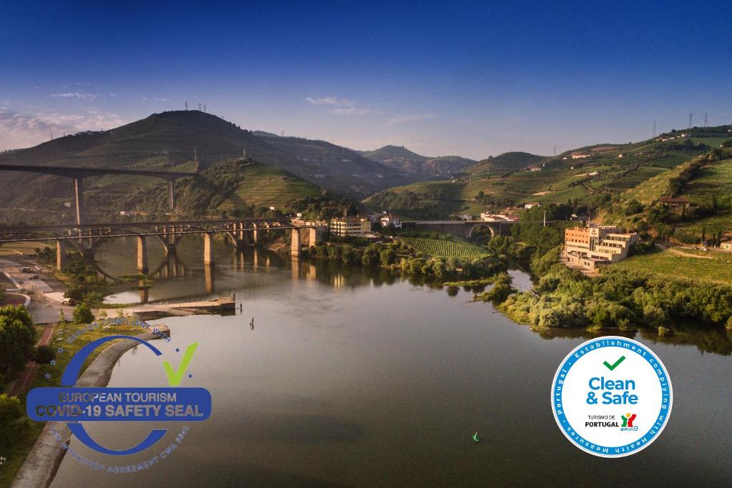 a view of a river with a bridge and hills at Vila Gale Collection Douro in Lamego