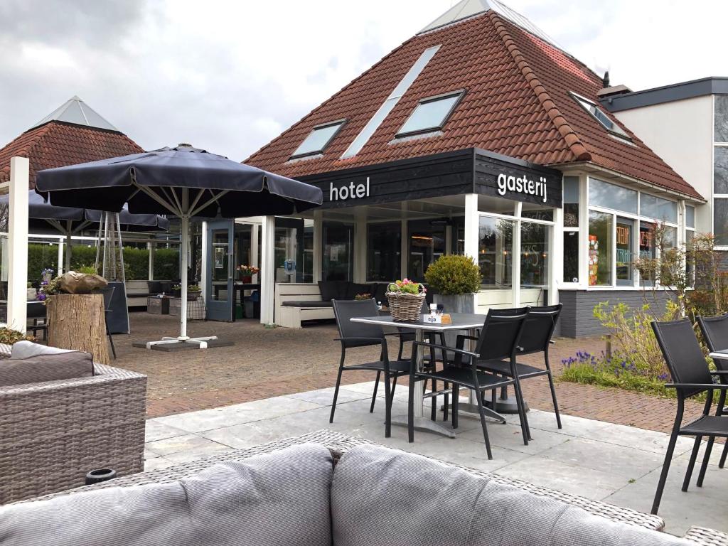 een restaurant met een tafel en stoelen en een parasol bij Hotel Molengroet in Noord-Scharwoude