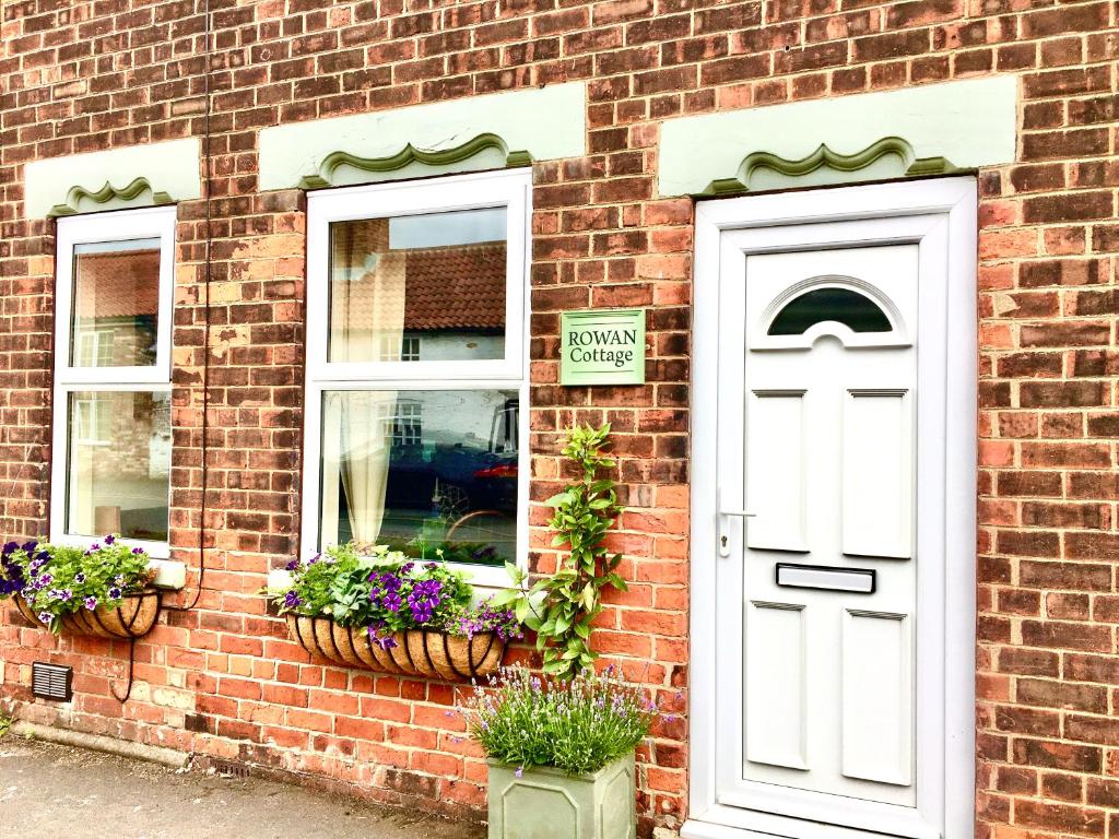 um edifício de tijolos com uma porta branca e duas janelas em Rowan Cottage em Ottringham