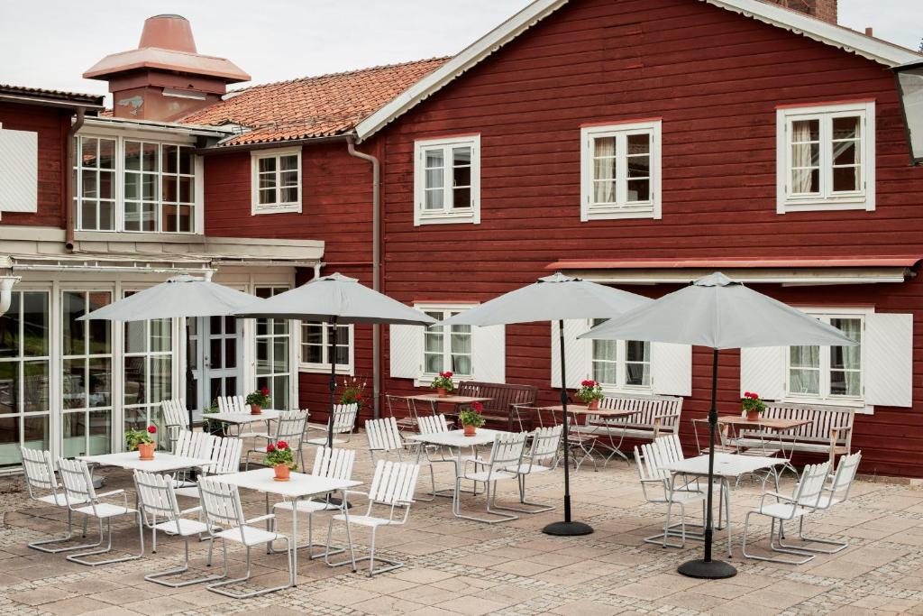 a group of tables and chairs with umbrellas in front of a building at Hotell Gyllene Hornet in Tällberg