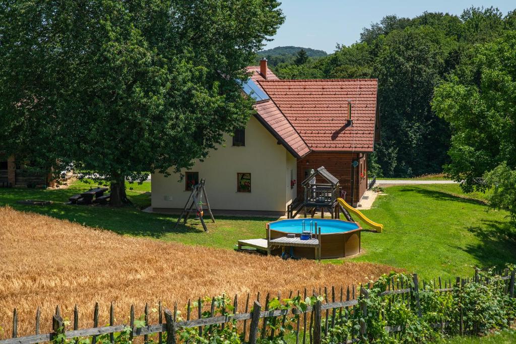 Tourist Farm Rajšp في Benedikt v Slovenskih Goricah: منزل صغير مع ملعب في الفناء