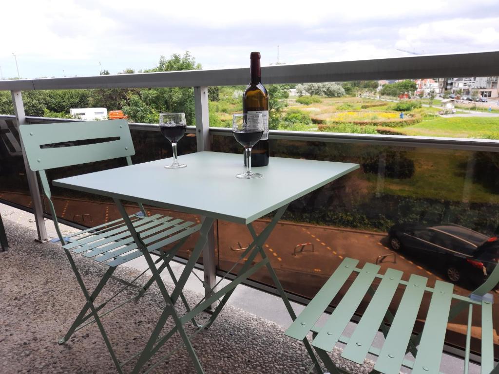 una mesa con 2 copas de vino en el balcón en Appartement Residentie Astrid met private parking, en Bredene