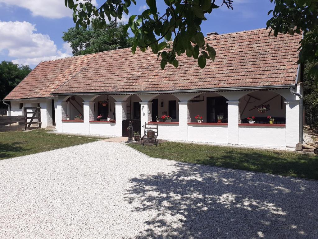 a white building with a roof on a field at Letűnt Idők Vendégház in Kemenesmihályfa