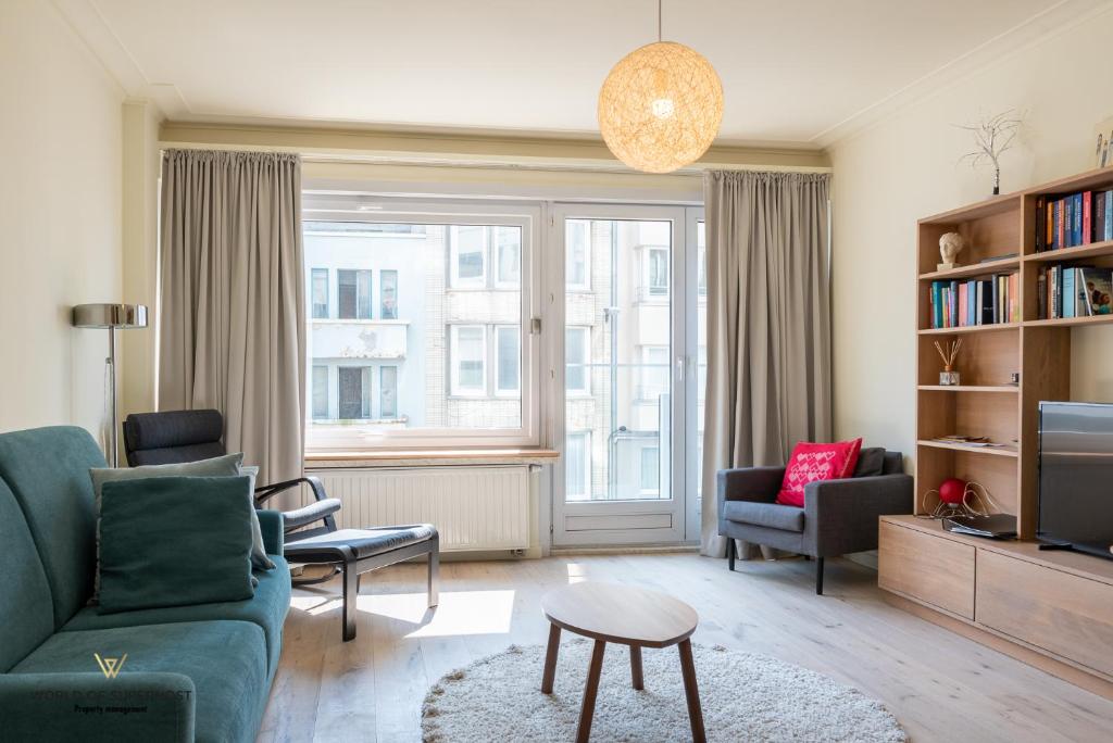 uma sala de estar com um sofá e cadeiras e uma televisão em Hélène, appartement vlakbij het strand em Oostende