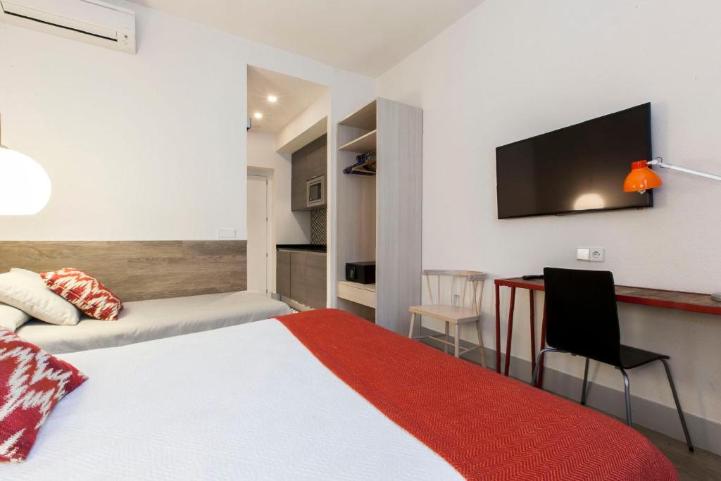 a bedroom with a bed and a desk and a tv at LOFTS Puerta del SOL in Madrid
