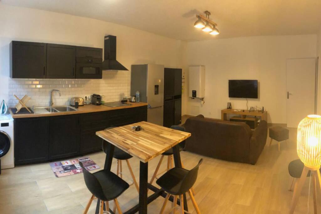 cocina y sala de estar con mesa y sofá en T2 neuf et Ambiance wood and black (noir et bois) en Saint-Étienne