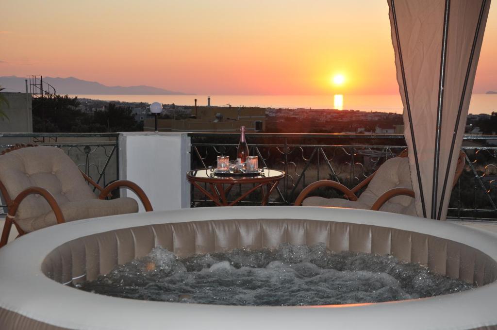 a hot tub on a balcony with a sunset in the background at Chersonissos Villa Elite in Hersonissos