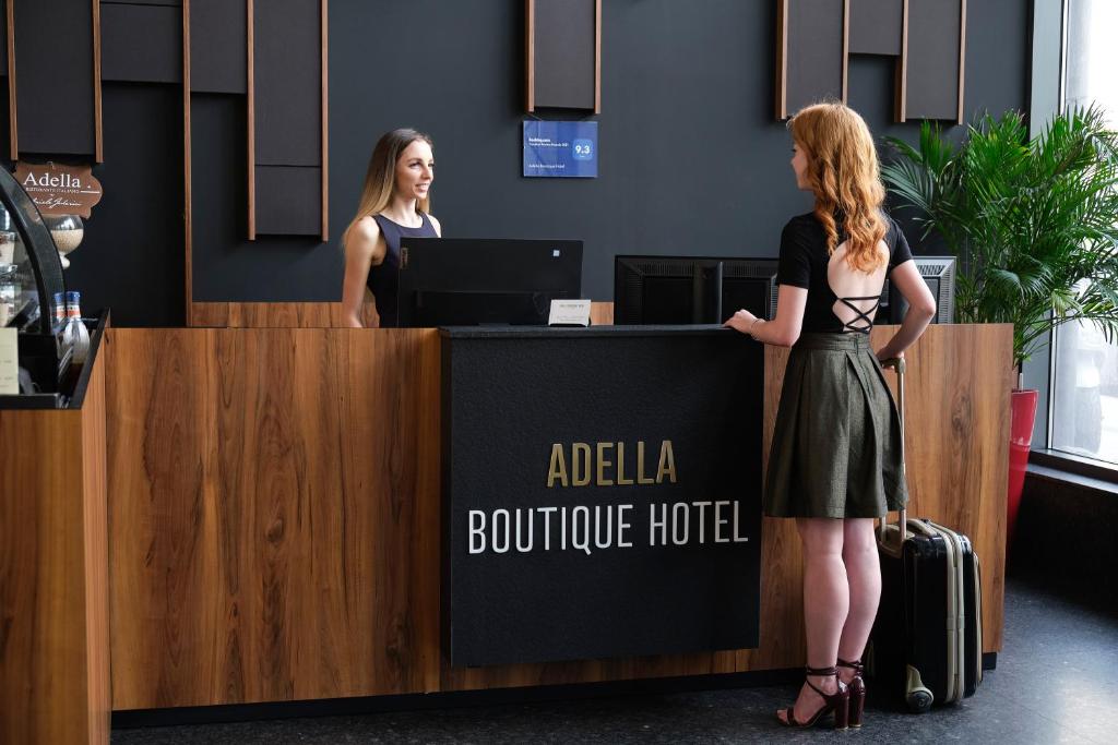 two women standing at a reception desk in an airport at Adella Boutique Hotel - Free Secured Parking in Sofia