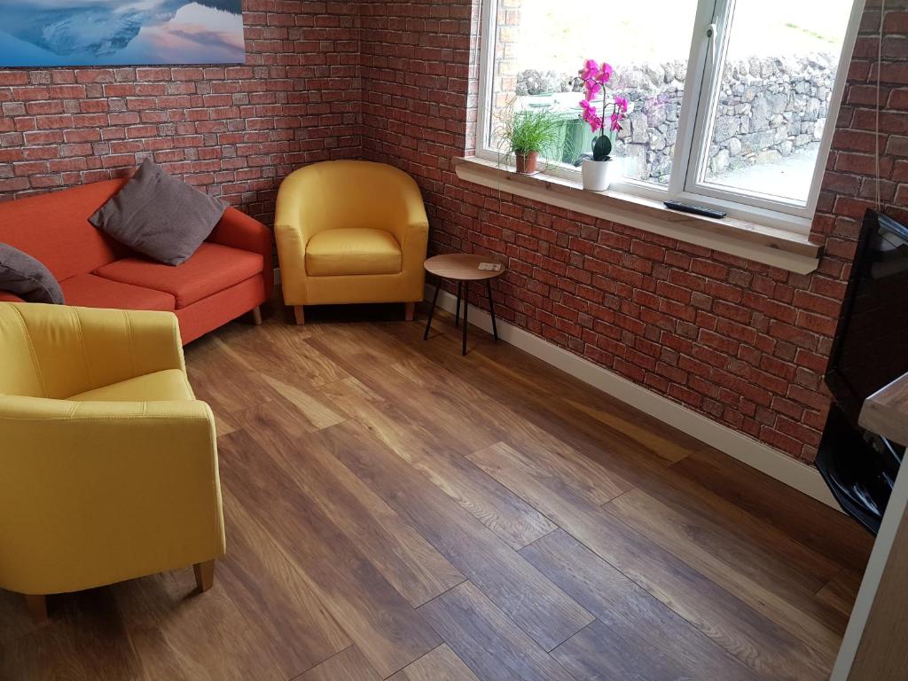 uma sala de estar com duas cadeiras e uma parede de tijolos em Skeabostview Brand New Self catering em Skeabost