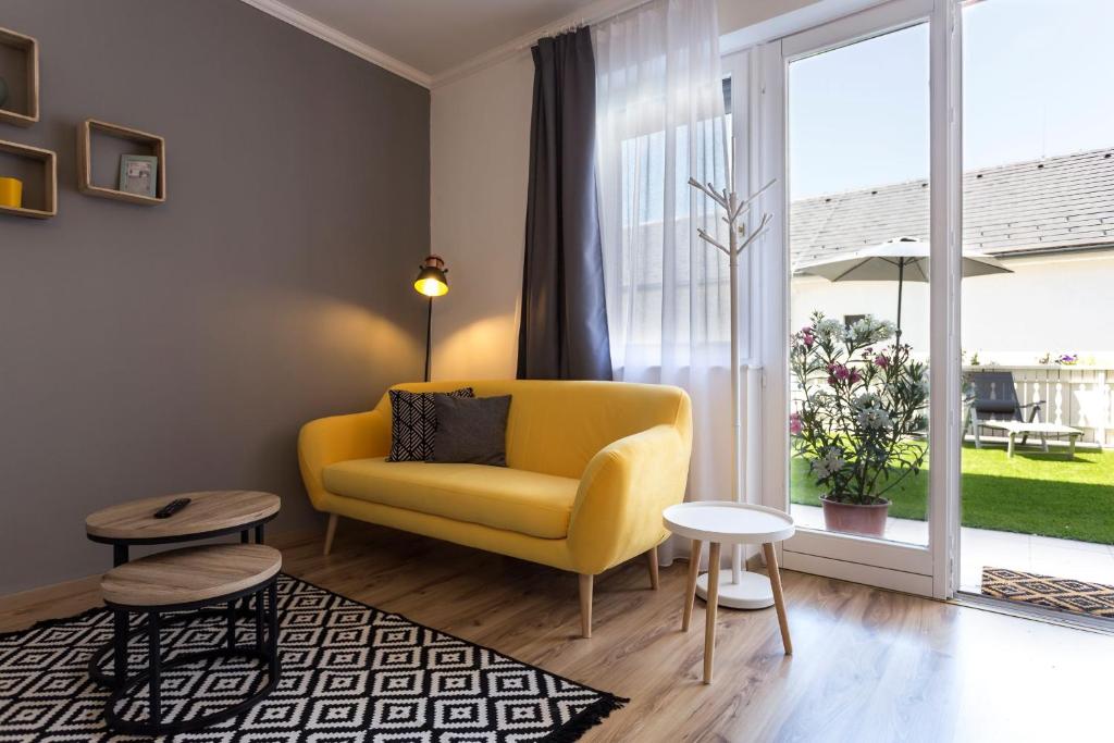 uma sala de estar com uma cadeira amarela e uma grande janela em Felhő Vendégház em Keszthely