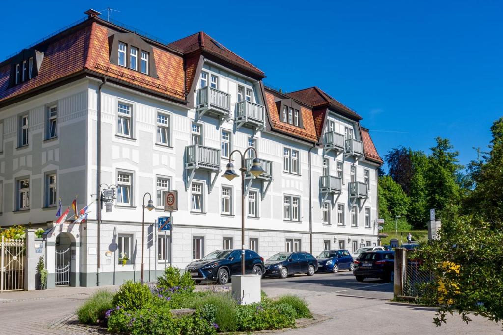 Aparthotel Hohenzollern في باد كيسينغن: مبنى ابيض كبير فيه سيارات تقف امامه