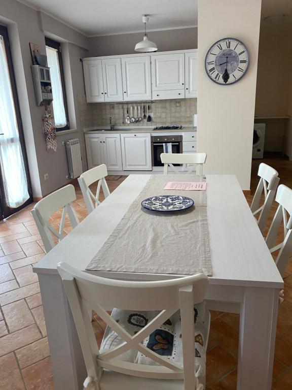 una mesa blanca y sillas en una cocina con reloj en Agriturismo Colle d' Oro, en Pescia Romana