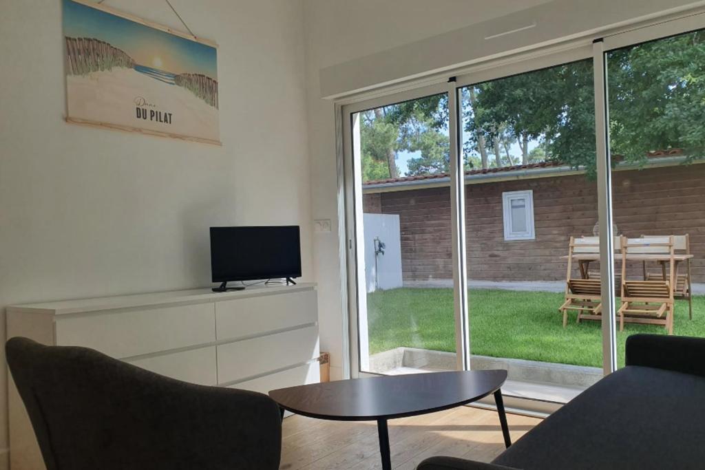 a living room with a tv and a table and a window at Charming Apt With Garden In Pilat Plage in La Teste-de-Buch