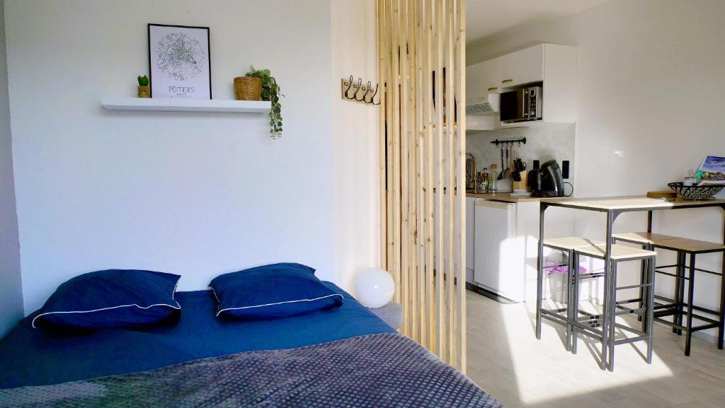 a bedroom with a blue bed and a kitchen at Studio à 8 min à pied du Futuroscope – 1&#47;4 pers in Chasseneuil-du-Poitou