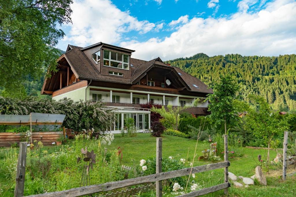 ein Haus auf einem Feld mit einem Zaun in der Unterkunft Naturoase Appartements Mirnock in Afritz