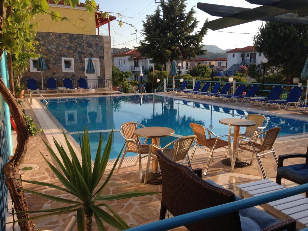 a swimming pool with chairs and tables in front of it at Anaxos Hotel in Anaxos