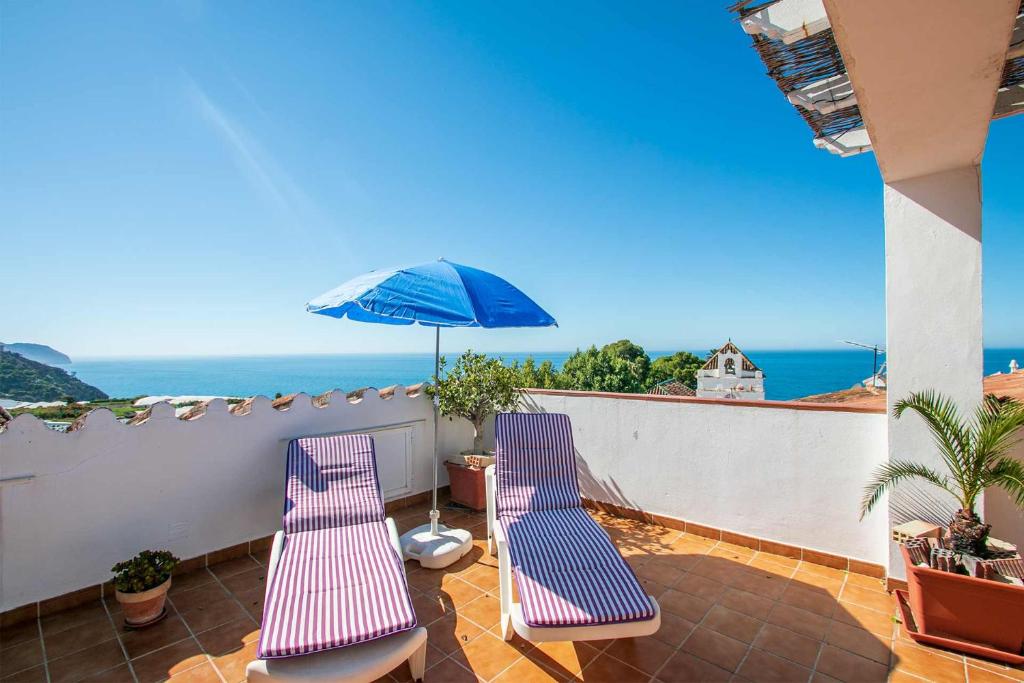 einen Balkon mit 2 Stühlen und einem Sonnenschirm in der Unterkunft Apartamentos Casa Yoli en Maro in Maro