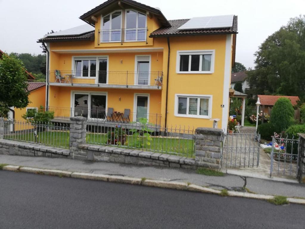 a yellow house with a fence in front of it at Ferienwohnung Rosemarie Wagner in Grafenau