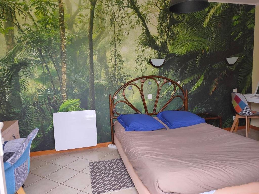 a bed with blue pillows in a room with a mural at chambre avec SDB privative en pleine campagne in Baillou