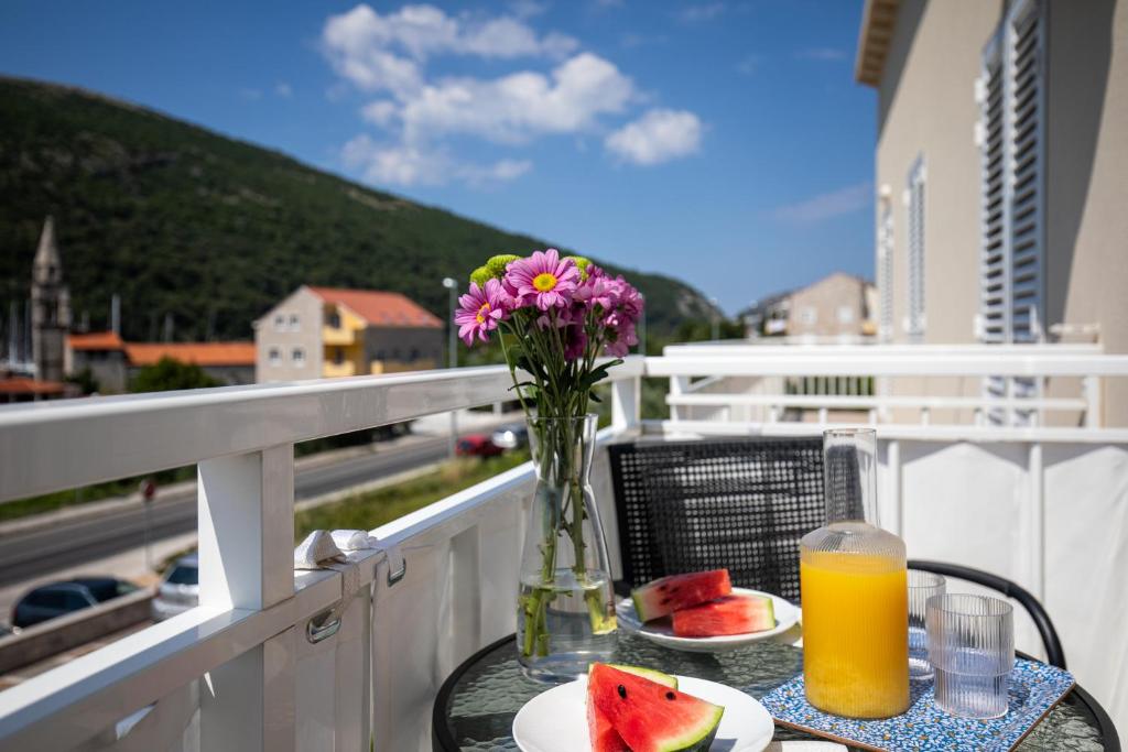 a table with a vase of flowers and fruit on a balcony at Apartments Silvija in Mokošica