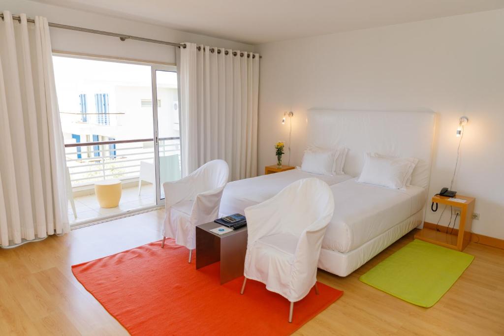 a bedroom with a white bed and a large window at Marina Club Lagos Resort in Lagos