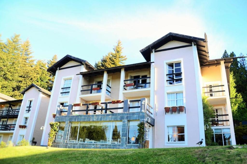 a large white building with a lawn in front of it at Aldea Andina Hotel San Carlos de Bariloche in San Carlos de Bariloche