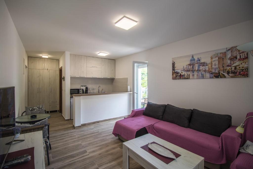 a living room with a purple couch and a kitchen at Studio Apartment Urke in Budva