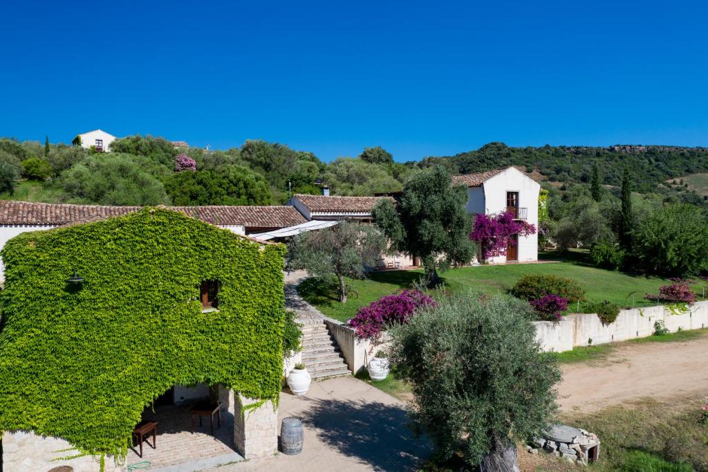 an ivy covered building with a yard and a house at Hotel S'Abba e Sa Murta in Tortolì