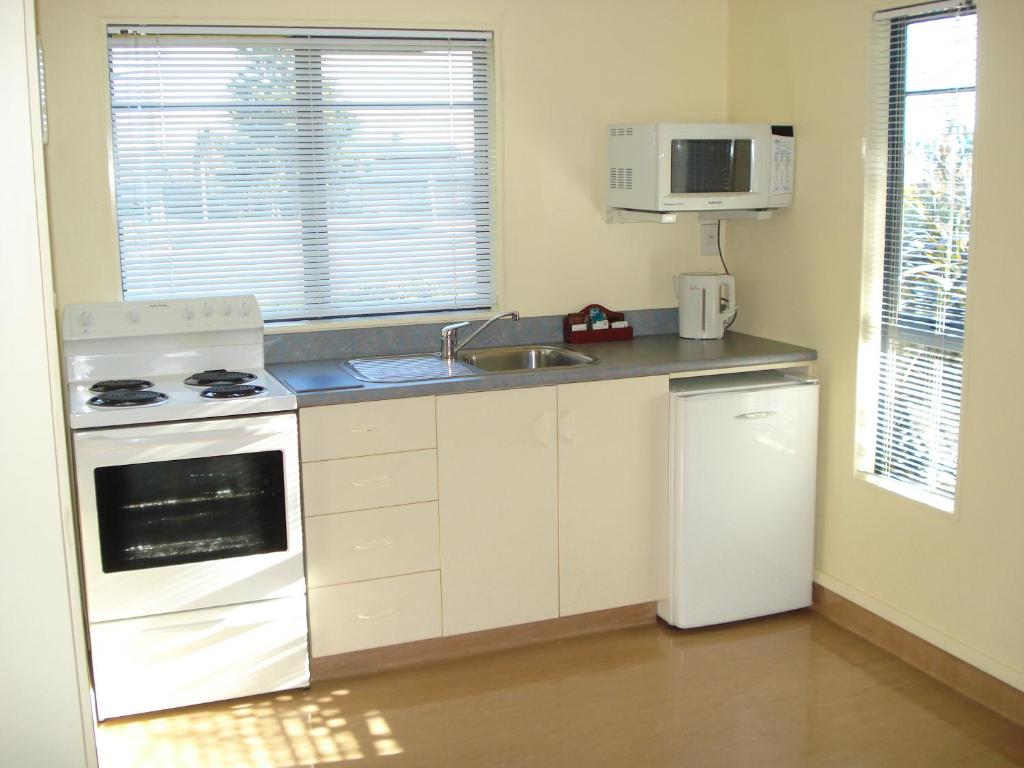 a kitchen with a stove and a sink and a microwave at The Peaks Motor Inn in Ohakune