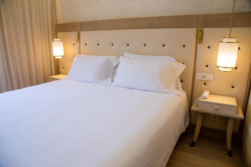 a bedroom with a white bed with two pillows at Vila Alba Resort in Carvoeiro