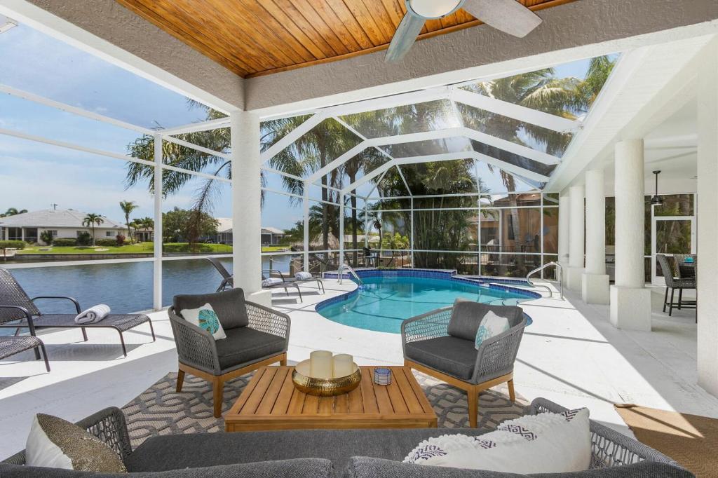 eine Terrasse mit Stühlen und einem Pool in der Unterkunft Villa Sunshine & Unwind - Cape Coral - Roelens Vacations in Cape Coral