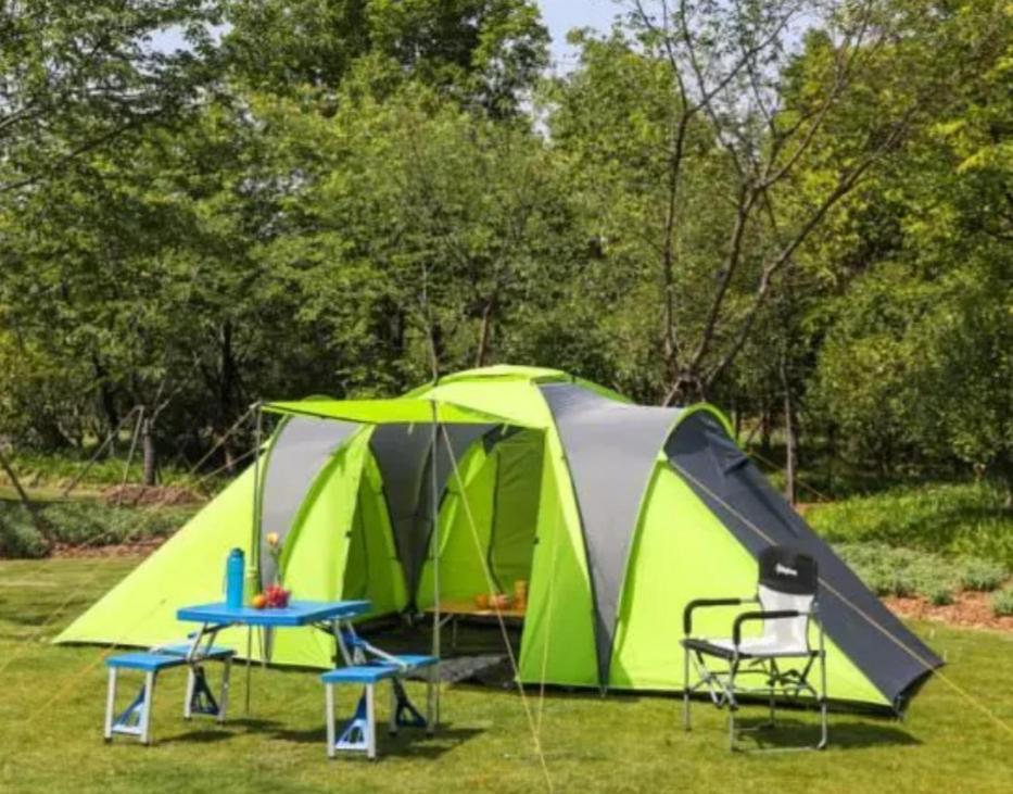 une tente, une table et des chaises dans un champ dans l'établissement Tente 3 chambres, petit camping familial vue mer, à Plestin-les-Grèves