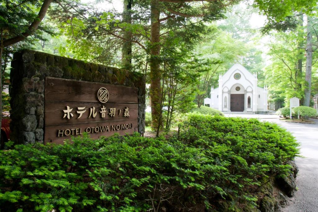 ein Schild vor einem Gebäude mit einer Kirche in der Unterkunft Kyu Karuizawa Hotel Otowa No Mori in Karuizawa