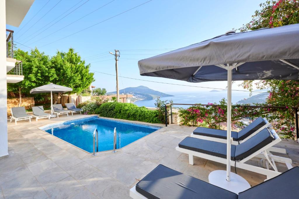 a swimming pool with two lounge chairs and an umbrella at Luxus Villa Skyla mit 5 Schlafzimmern & Meer-Blick in Kas