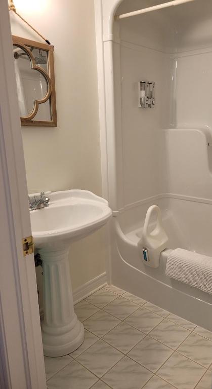 a white bathroom with a sink and a bath tub at La Maison de Sophie in Niagara-on-the-Lake