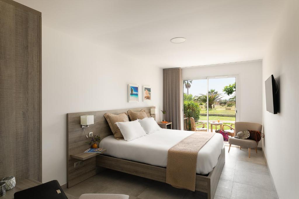 um quarto de hotel com uma cama e uma janela em Hôtel-Restaurant Marina Di Lava - Grand Ajaccio em Appietto