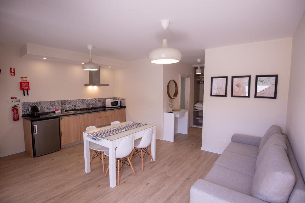 a kitchen and a living room with a table and a couch at Refúgio do Avô - Vale de Lourinhã in Lourinhã