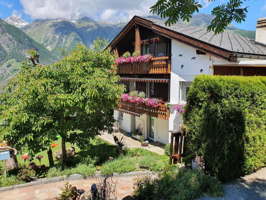 ein Haus mit einem Balkon mit Blumen darauf in der Unterkunft Chalet Schneevogul in Grächen